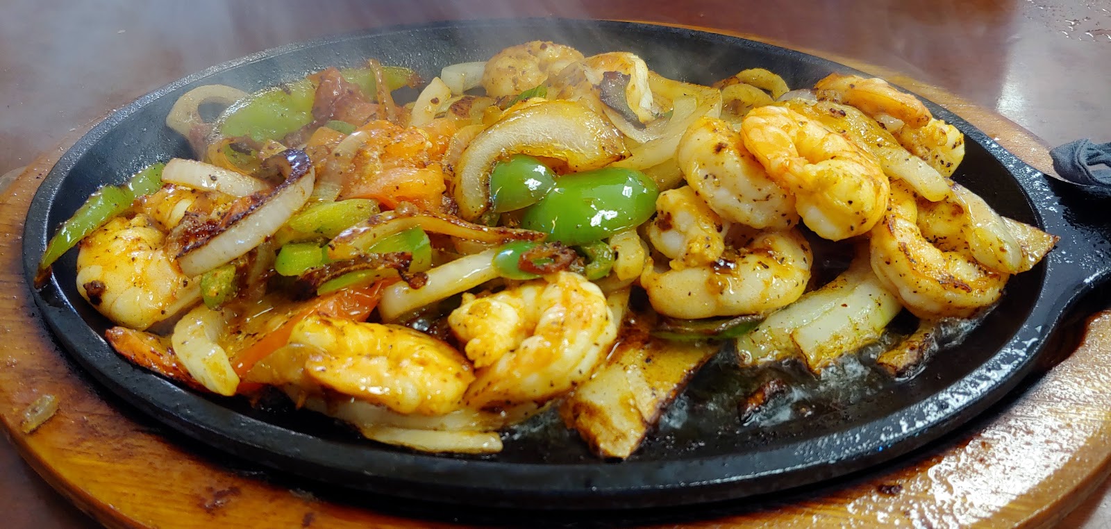 Sizzling shrimp and steak fajitas on a hot cast-iron platter at Taqueria La Tapatia