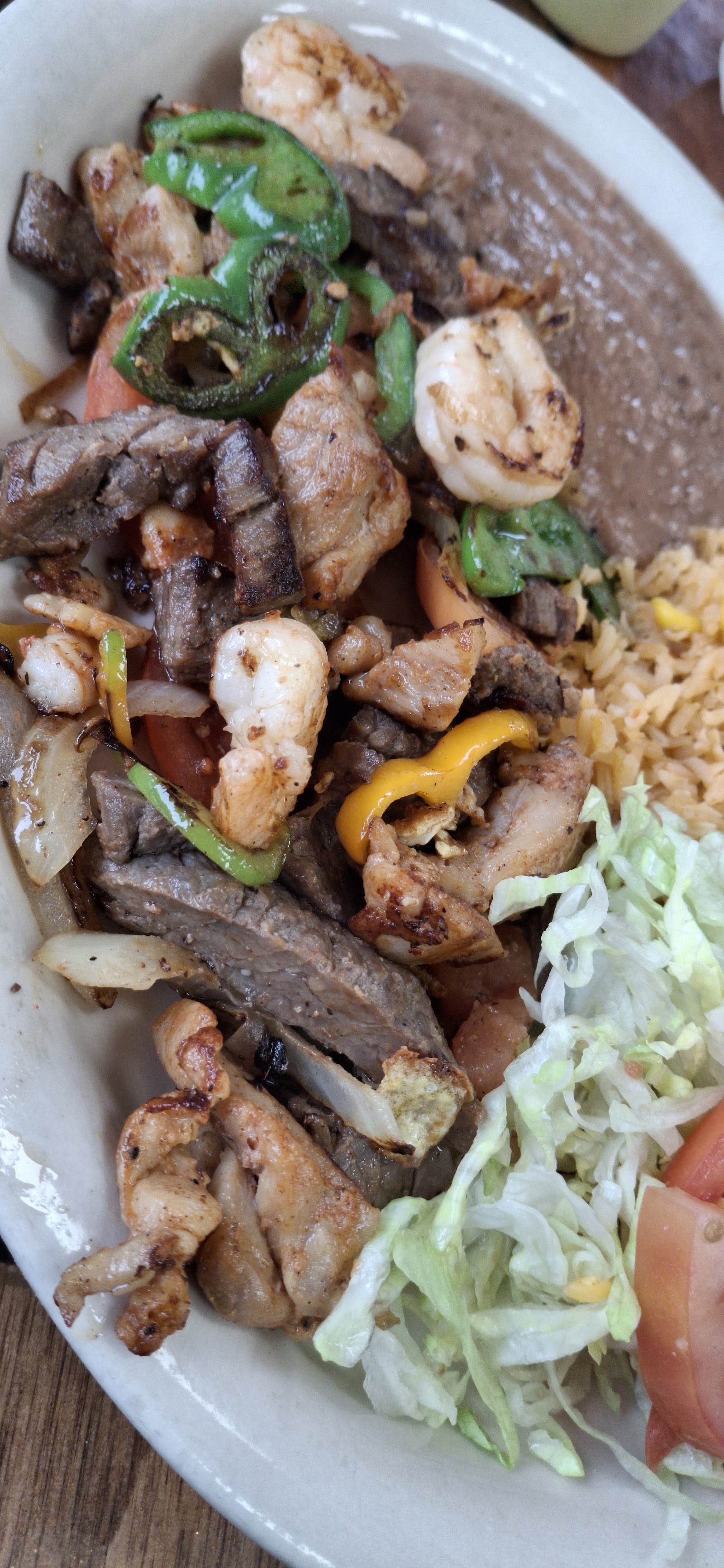 Mixed grill plate with steak, chicken and shrimp, rice, beans and salad